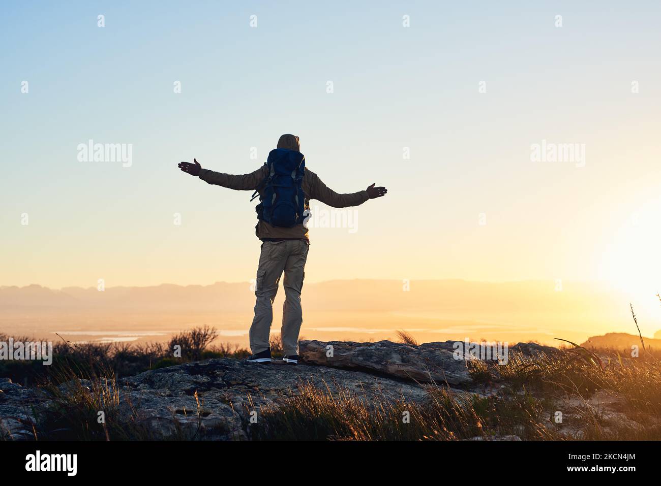 The world is your oyster. a hiker with his arms raised standing on top of a mountain. Stock Photo