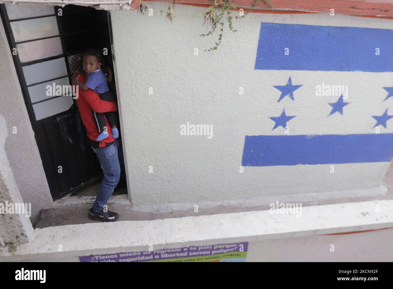 A Haitian migrant carries his son outside a room on the roof of the
