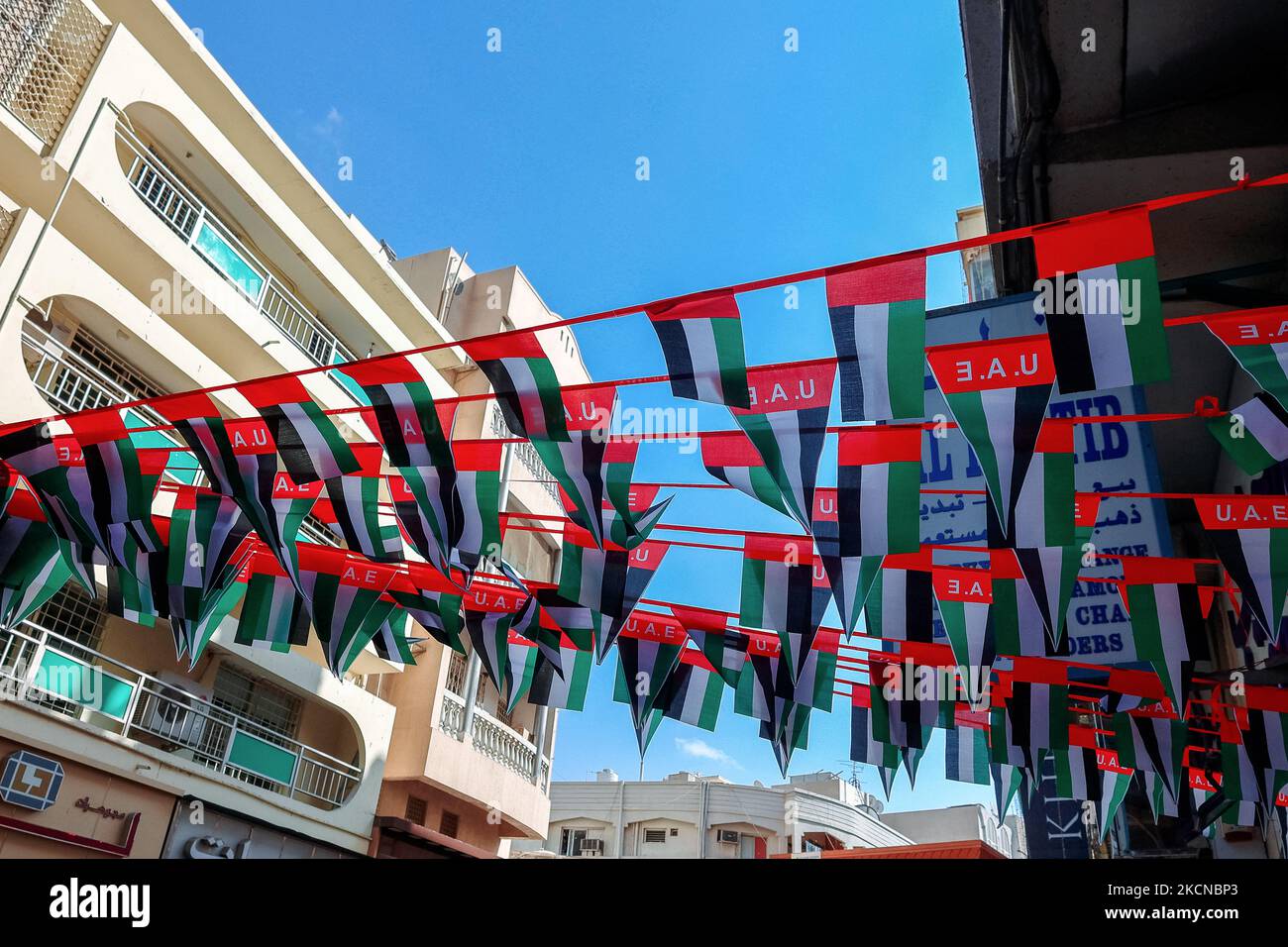 UAE, Dubai - November 29, 2021: Hanging decorations from many national flags of United Arab Emirates on street of Dubai. Natoinal Day UAE. Flags in rows waving in wind against blue sky.  Stock Photo