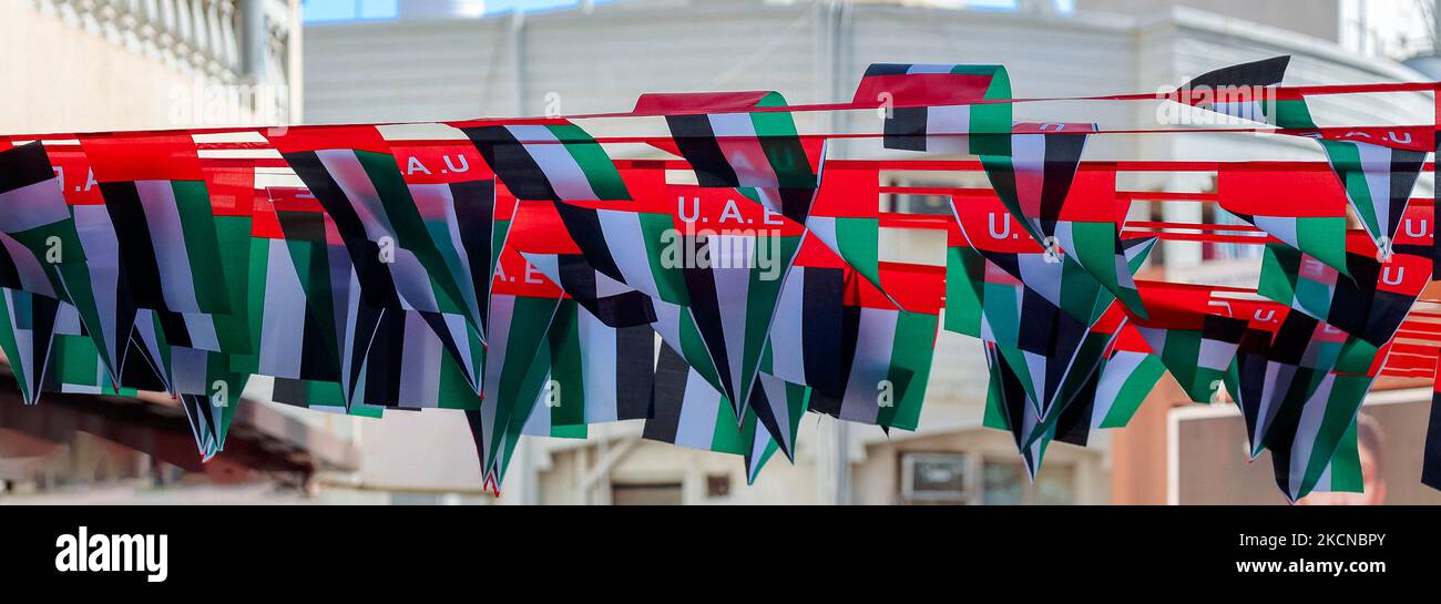 Hanging decorations from many national flags of United Arab Emirates on street of Dubai. Natoinal Day UAE. Flags in rows waving in wind against blue sky. High quality photo Stock Photo