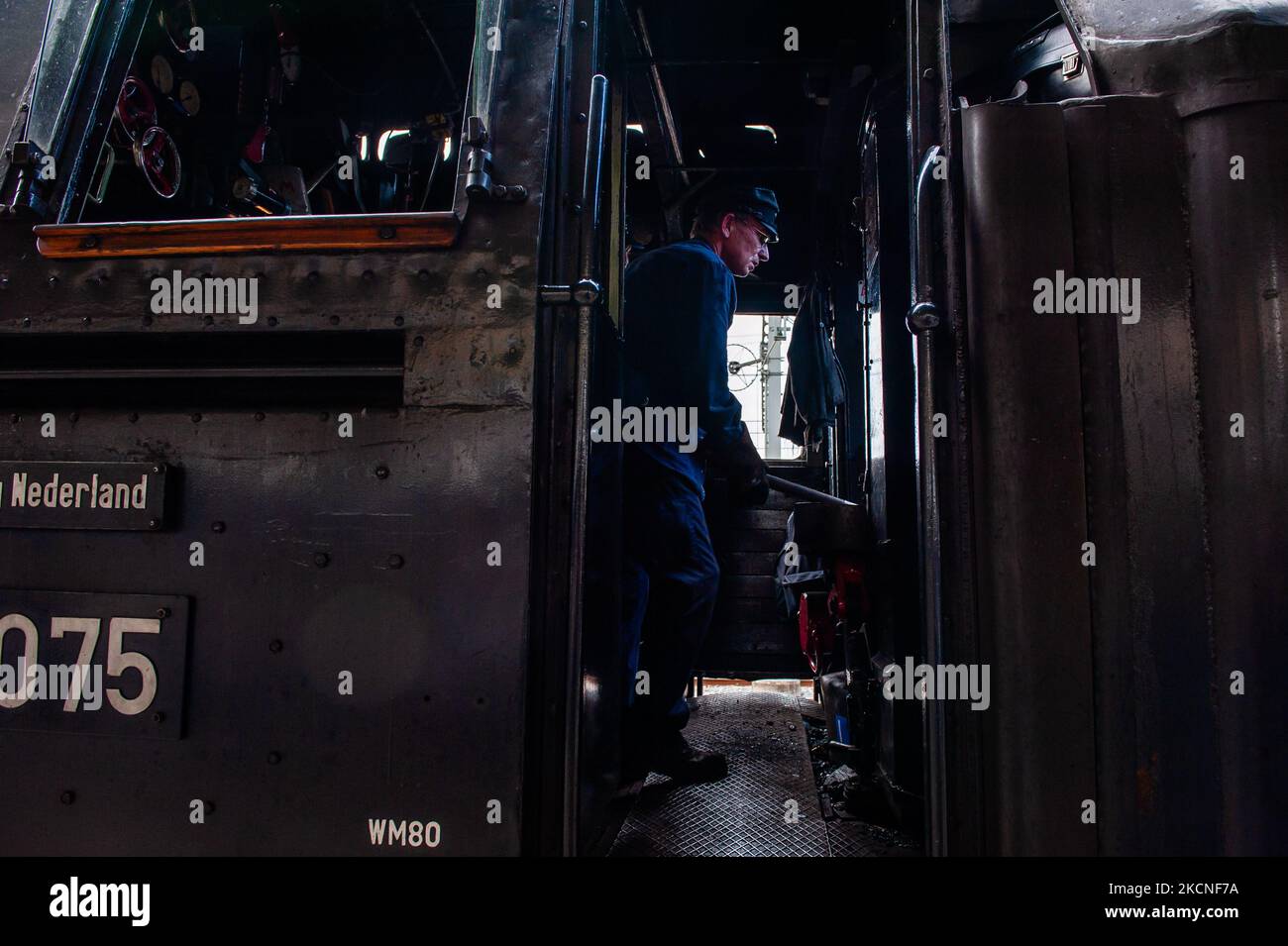 A train driver is feeding fuel into the boiler of the 40's German ...