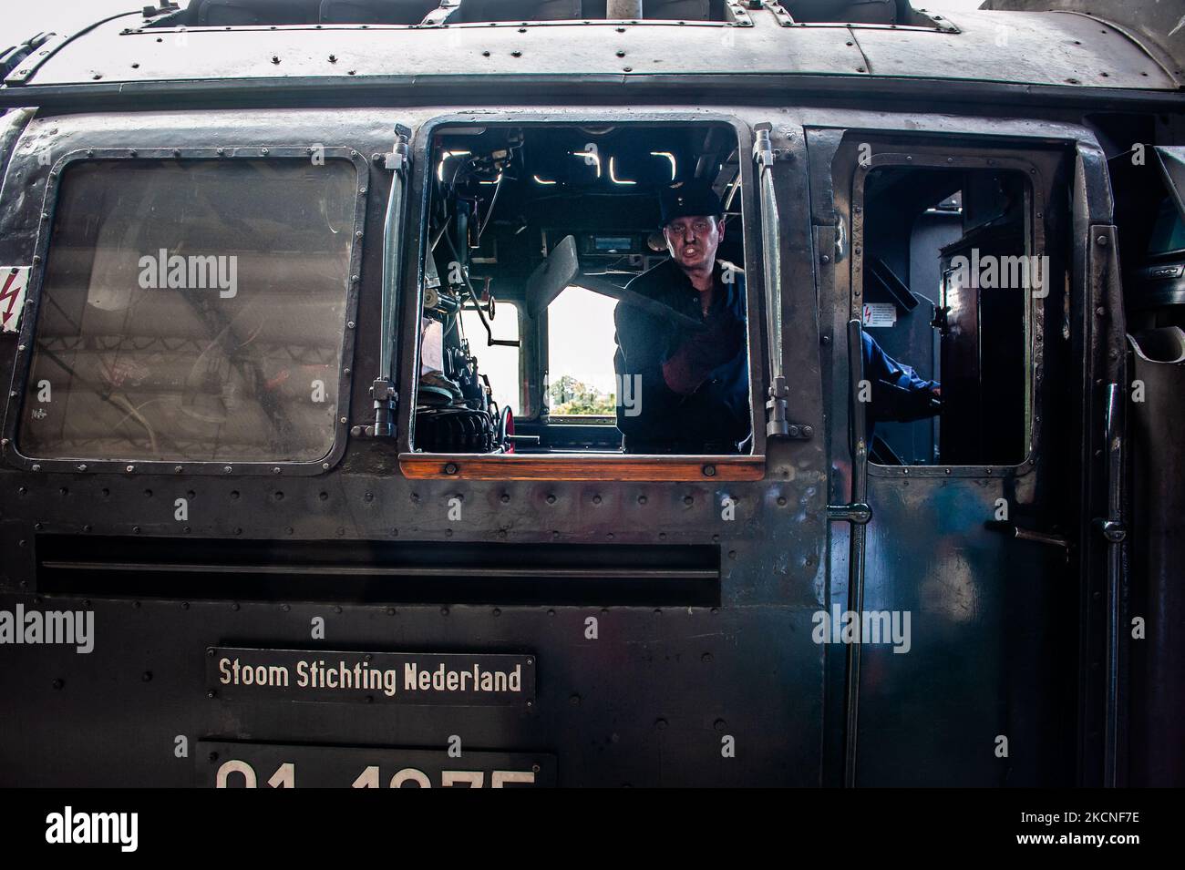 A train driver is feeding fuel into the boiler of the 40's German ...