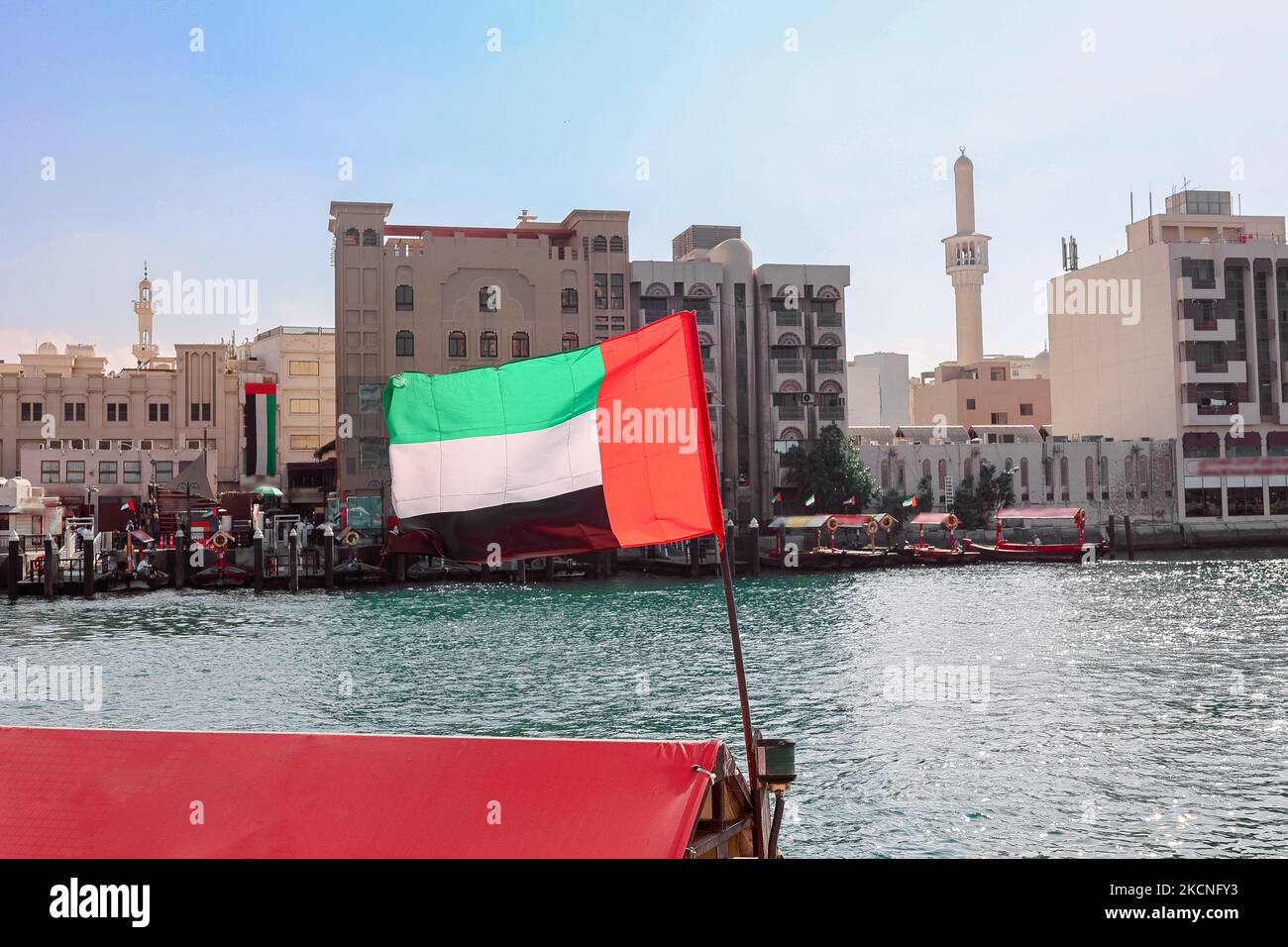 Big flag of United Arab Emirates flying high on city of Dubai in old town. Natoinal Day UAE. High quality photo Stock Photo