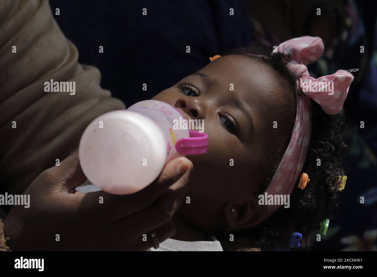A Haitian migrant mother offers milk to her daughter outside the Mexican Commission for Refugee Support in Mexico City, where more migrants recently went to various refugee support offices to try to obtain a procedure that would allow them to stay longer in Mexico in the face of the difficulties their compatriots are having in entering the United States during the COVID-19 health emergency. (Photo by Gerardo Vieyra/NurPhoto) Stock Photo