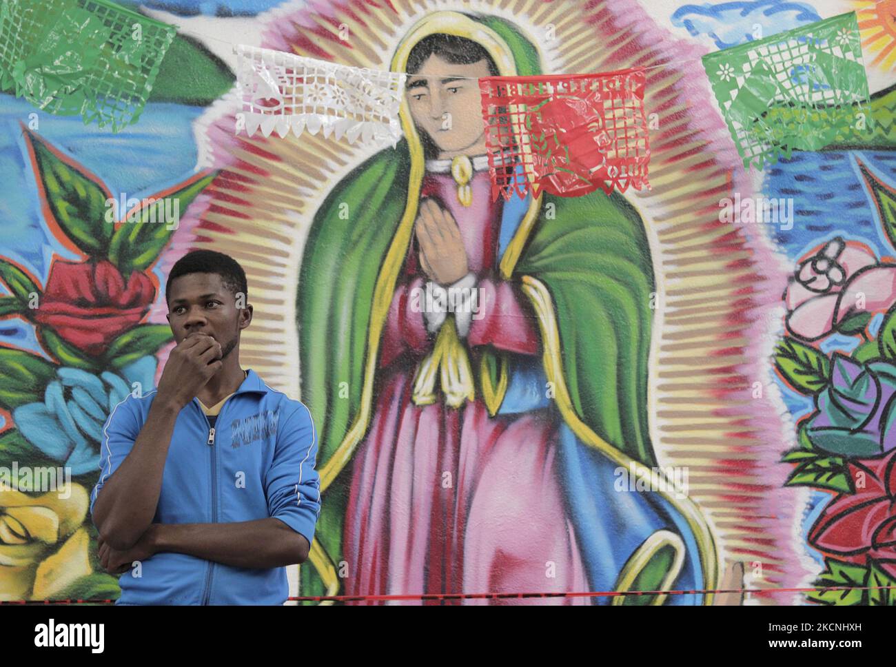 A Haitian migrant in front of a mural of the Virgin of Guadalupe inside the Casa de Acogida Formación y Empoderamiento de la Mujer Migrante y Refugiada (CAFEMIN), located in Mexico City, Mexico, on September 27, 2021, which offers lodging and food to migrants who recently went to various refugee support offices to try to obtain a permit to stay longer in Mexico in view of the difficulties their compatriots are having in entering the United States during the COVID-19 health emergency. (Photo by Gerardo Vieyra/NurPhoto) Stock Photo