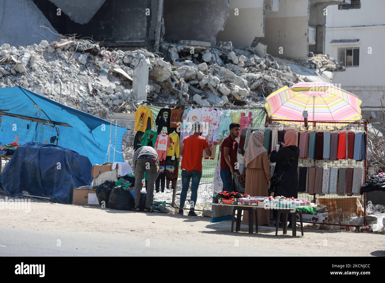 Women shop next to the rubble of destroyed buildings hit by Israeli airstrikes during an 11-day war between Gaza's Hamas rulers and Israel, at the main shopping road in Gaza City, on September 28, 2021. (Photo by Majdi Fathi/NurPhoto) Stock Photo