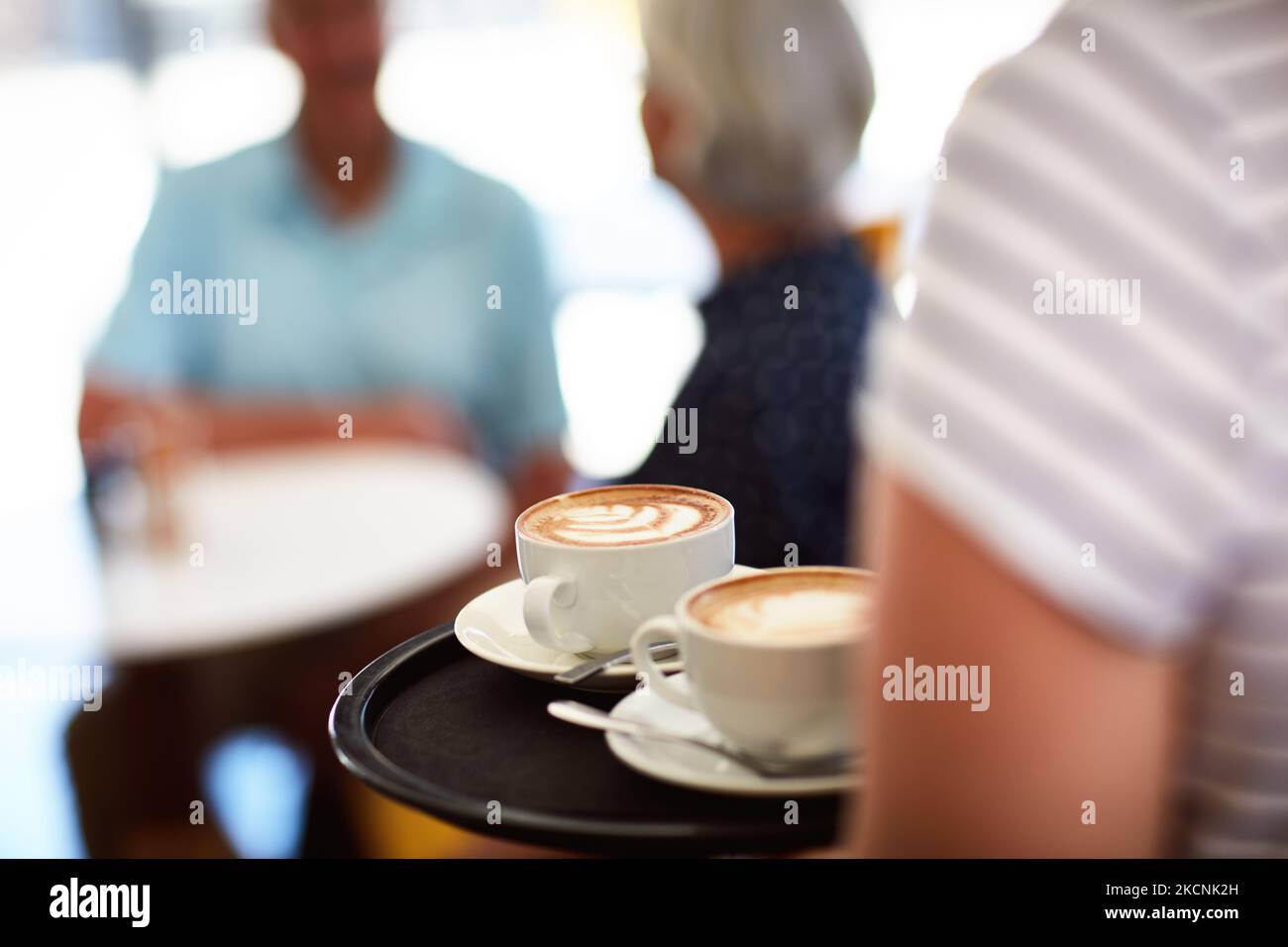 Your coffee break never looked so good. a waitress carrying two coffees