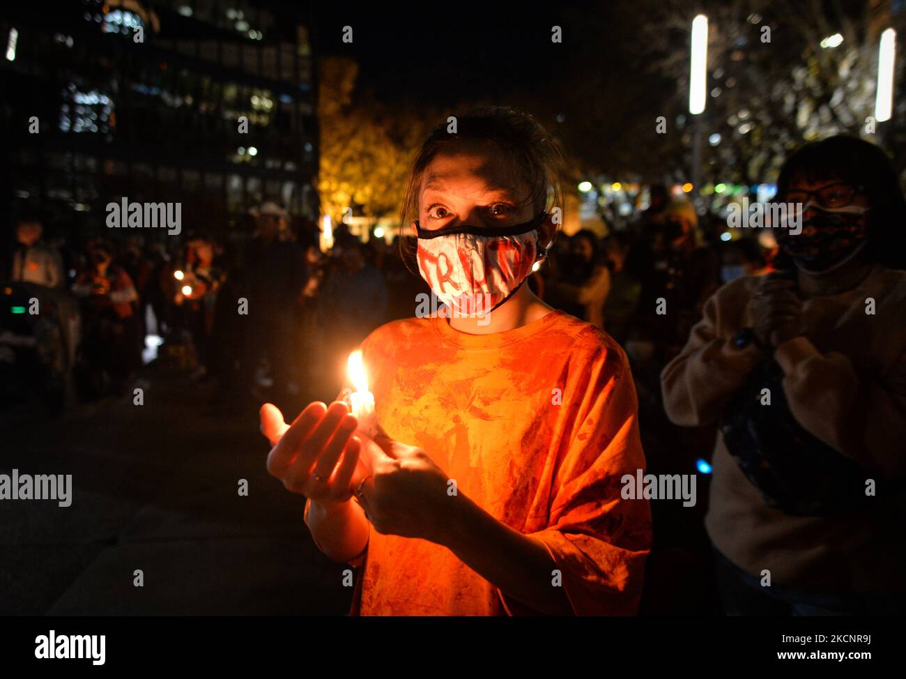 A young woman holds a candle during a candlelight vigil at the ...