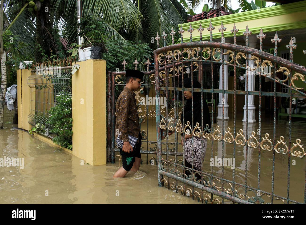 People are seen walking through floods caused by a river overflowing after heavy rains in North Aceh, on October 1, 2021, Aceh Province, Indonesia. (Photo by Fachrul Reza/NurPhoto) Stock Photo