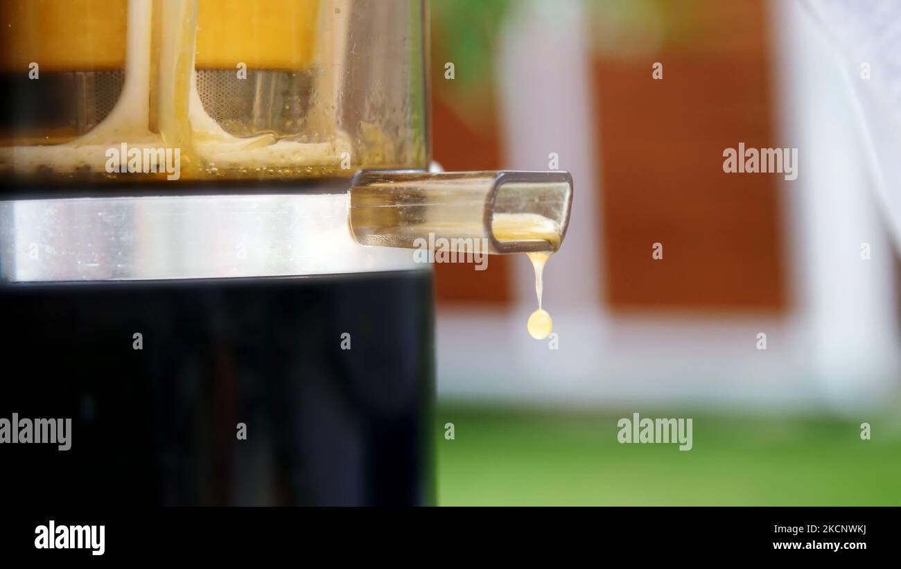 close-up, drops of freshly squeezed orange juice drip from the juicer. High quality photo Stock Photo