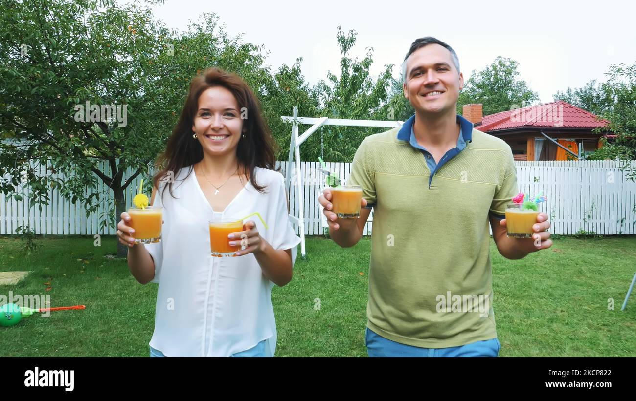 summer, in the garden, parents, mom and dad, carry freshly squeezed fruit juice to treat their children. The family spends their leisure time together. High quality photo Stock Photo
