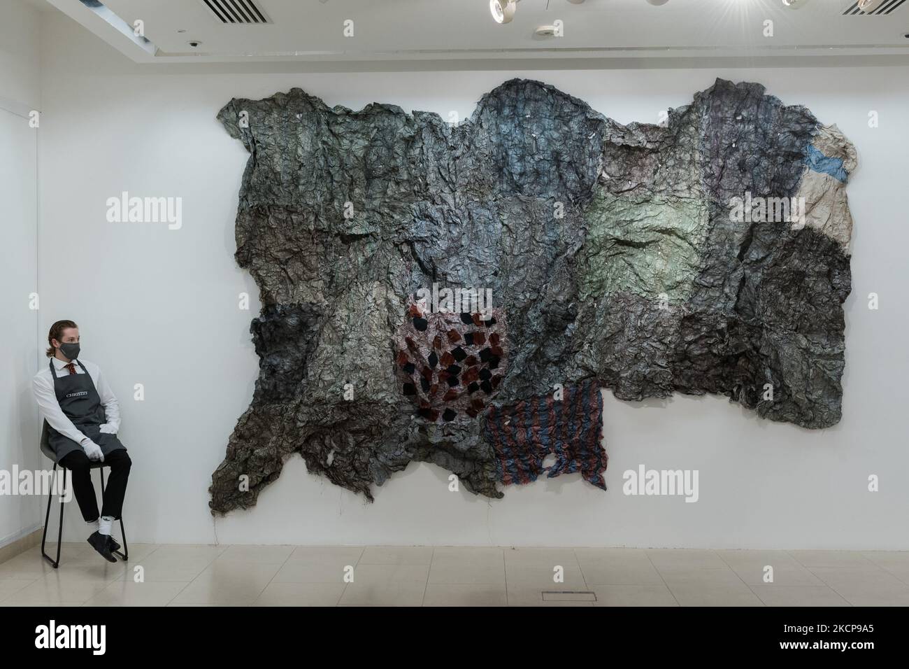LONDON, UNITED KINGDOM - OCTOBER 08, 2021: A staff member looks at an artwork by Elolo Bosaka (b. 1991) 'Pourquoi les lunettes sont noires?', 2020, part of REDEFINING THE TREND – Histories in the Making curated exhibition, during a press preview of 20th/21st Century: Evening Sale at Christie's auction house on October 08, 2021 in London, England. (Photo by WIktor Szymanowicz/NurPhoto) Stock Photo