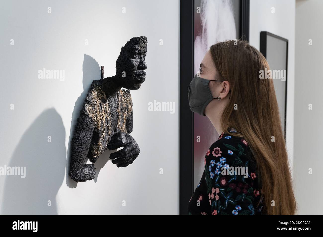 LONDON, UNITED KINGDOM - OCTOBER 08, 2021: A staff member looks at a sculpture 'Serenity' by Richard Atugonza (b. 1994), part of REDEFINING THE TREND – Histories in the Making curated exhibition, during a press preview of 20th/21st Century: Evening Sale at Christie's auction house on October 08, 2021 in London, England. (Photo by WIktor Szymanowicz/NurPhoto) Stock Photo