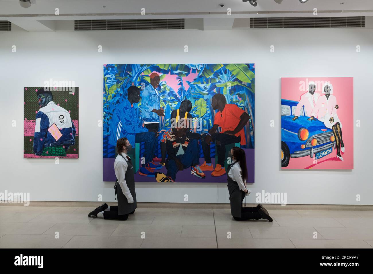 LONDON, UNITED KINGDOM - OCTOBER 08, 2021: Staff members pose with (L-R) 'Greatness is Within', 2021, by Anjel, 'Blue night romance', 2019, by Marc Padeu and 'Me, You and Big Blue', 2021, by Zeh Palito, part of REDEFINING THE TREND – Histories in the Making curated exhibition, during a press preview of 20th/21st Century: Evening Sale at Christie's auction house on October 08, 2021 in London, England. (Photo by WIktor Szymanowicz/NurPhoto) Stock Photo