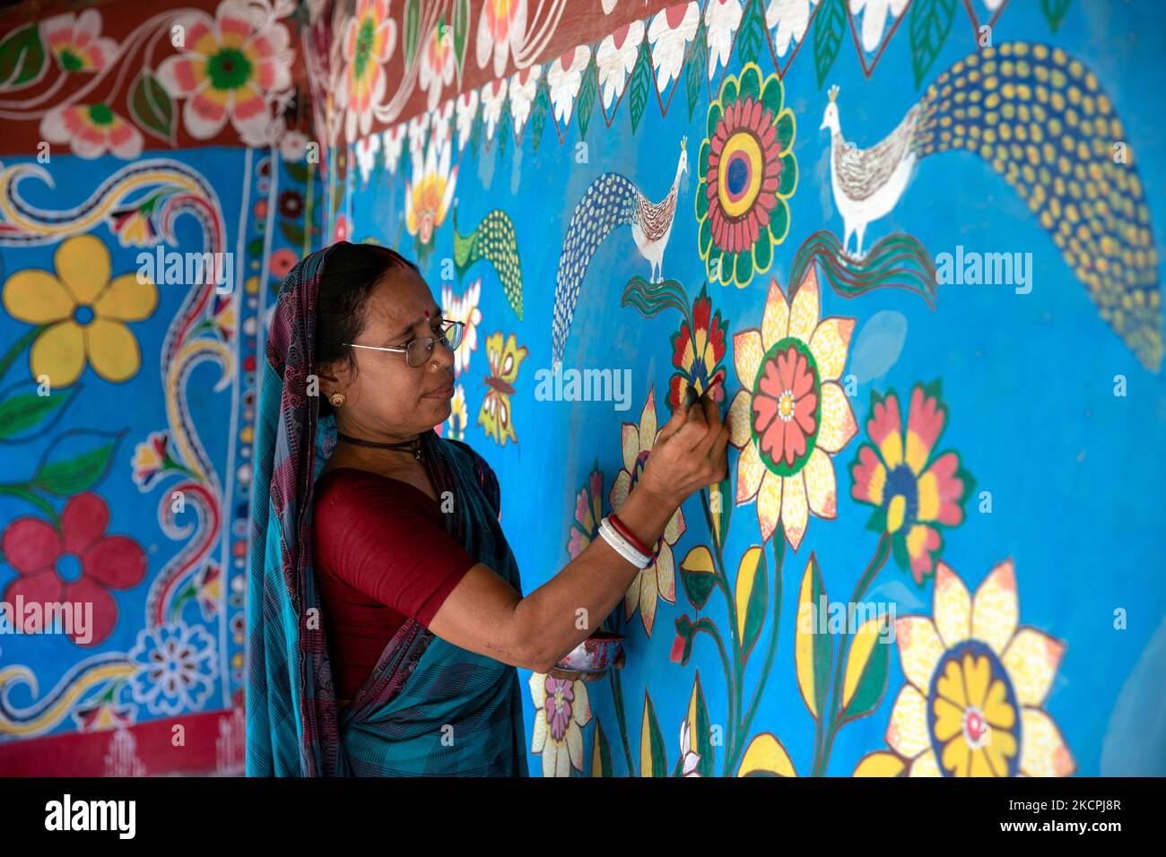 A woman draws traditional motifs on a wall of her house at Tikoil village in Nachole upazila of Chapainawabganj district of Bangladesh. (Photo by Mushfiqul Alam/NurPhoto) Stock Photo