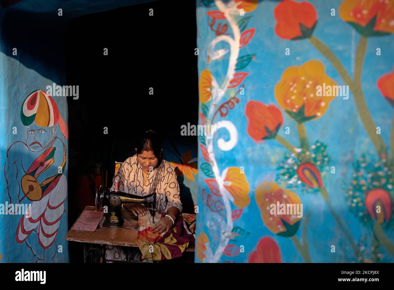Joya Barman stitches clothes with her sewing machine inside her colorful house in alpona village in chapainawabganj, Bangladesh. (Photo by Mushfiqul Alam/NurPhoto) Stock Photo