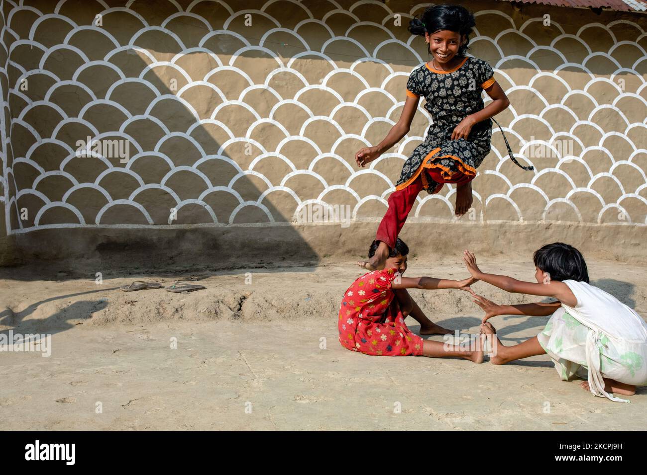 Children play the traditional game in front of a painted wall in alpona village in chapainawabganj, Bangladesh (Photo by Mushfiqul Alam/NurPhoto) Stock Photo