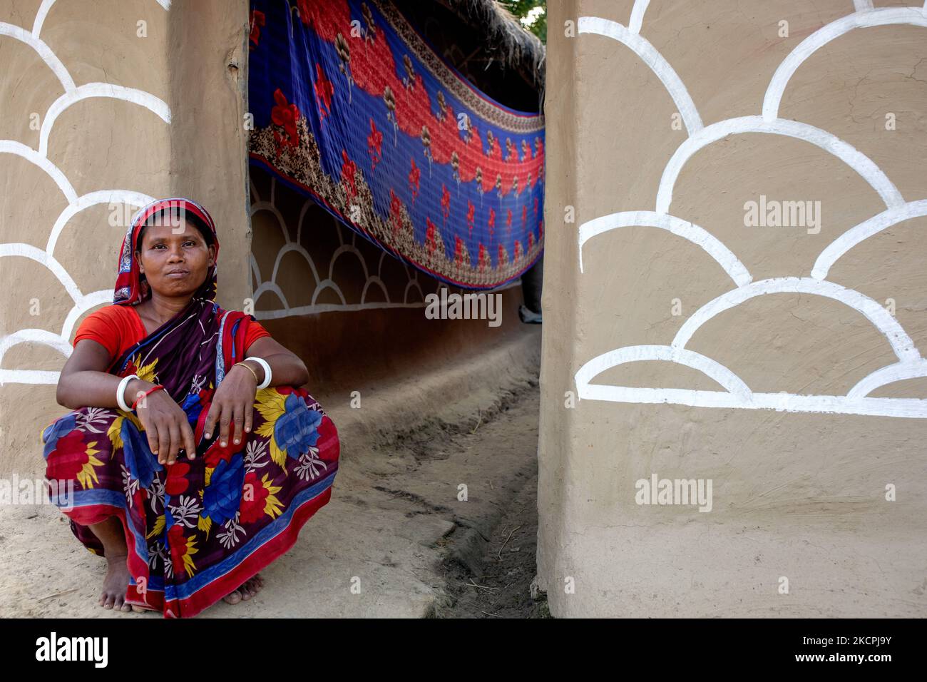 A woman poses in front of her painted house in alpona village in chapainawabganj, Bangladesh. (Photo by Mushfiqul Alam/NurPhoto) Stock Photo