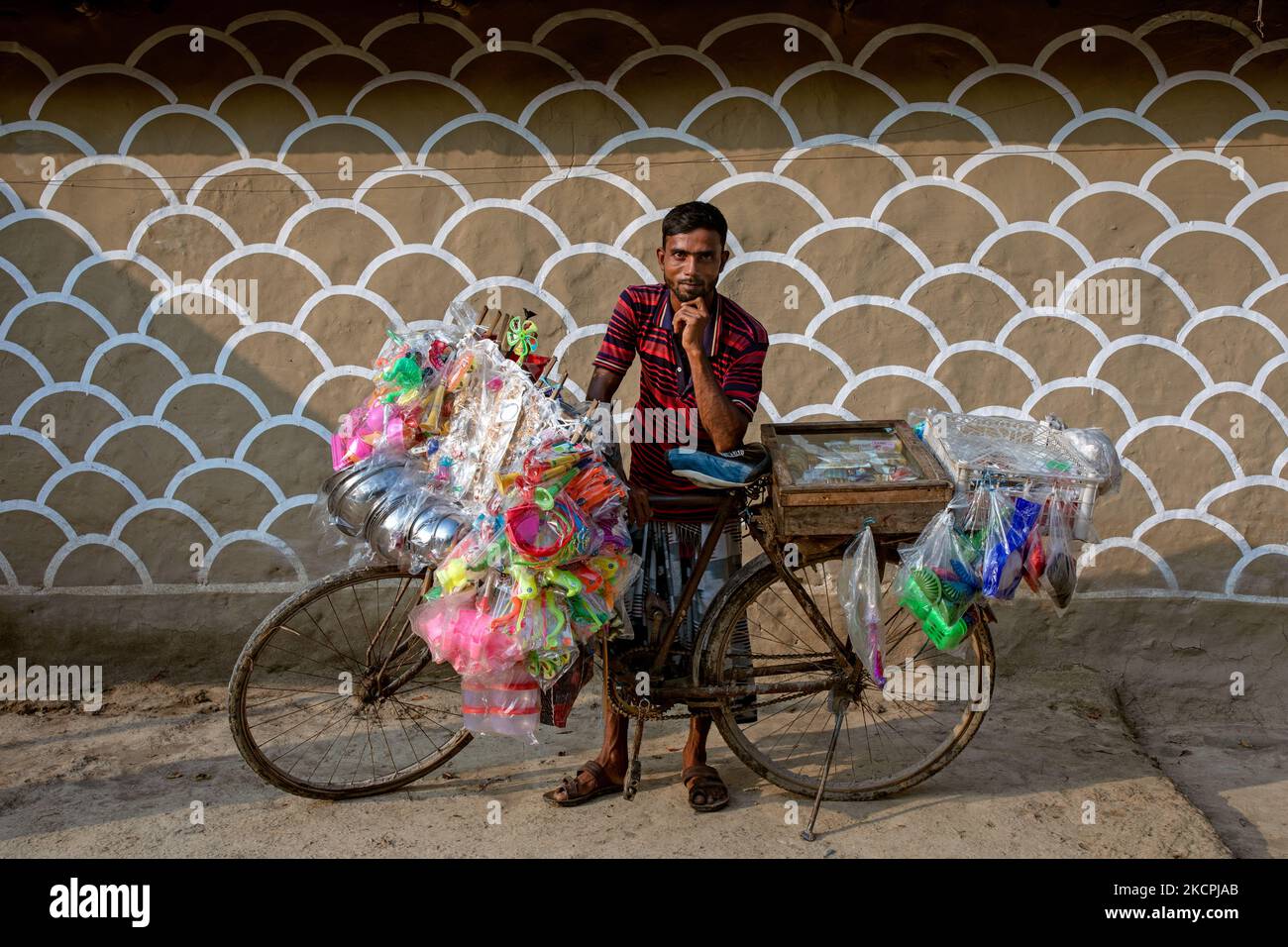 A traditional street vendor poses in front of a painted wall in alpona village in chapainawabganj, Bangladesh (Photo by Mushfiqul Alam/NurPhoto) Stock Photo