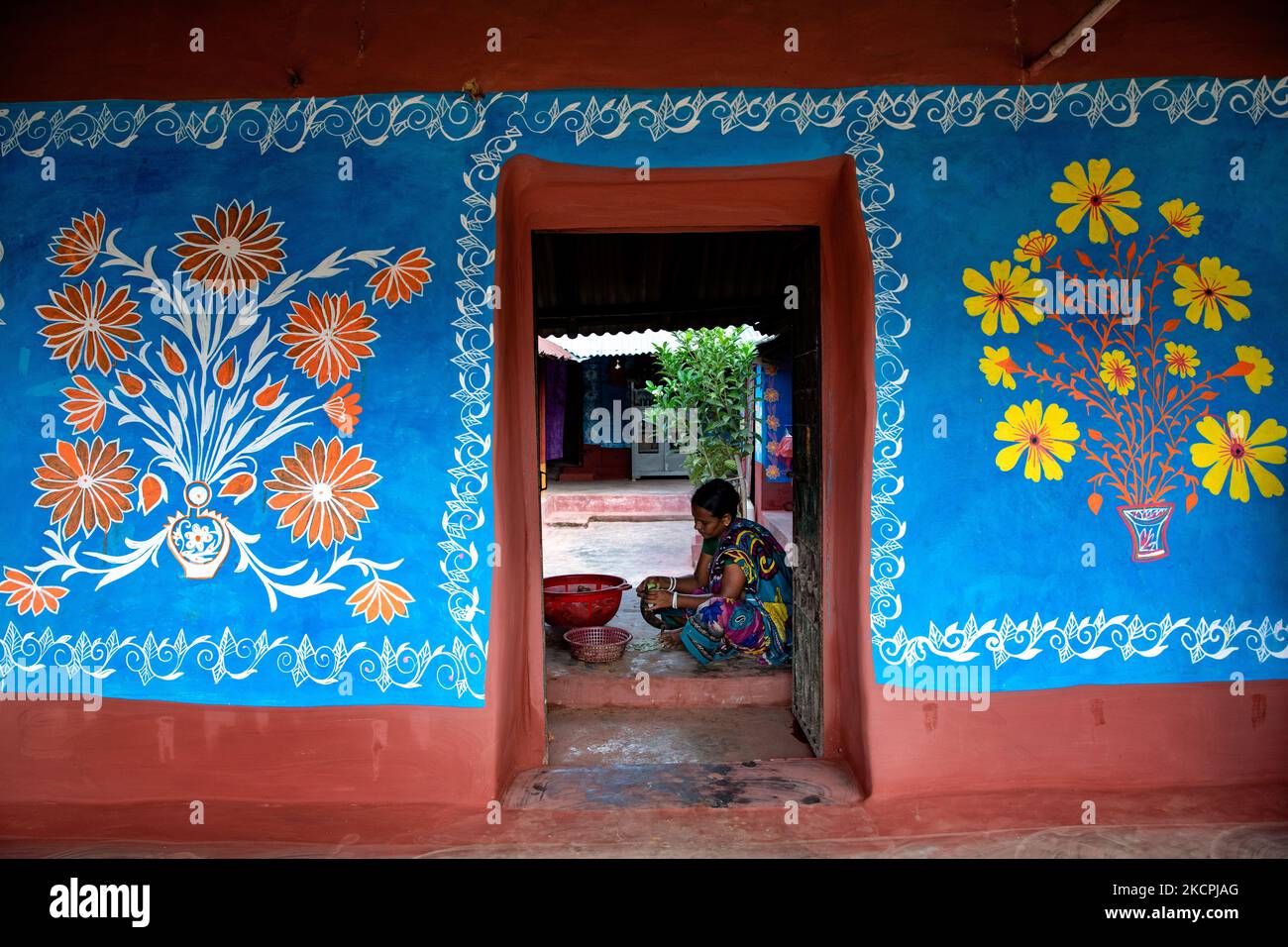A woman works inside her colorful painted house in alpona village in chapainawabganj, Bangladesh (Photo by Mushfiqul Alam/NurPhoto) Stock Photo
