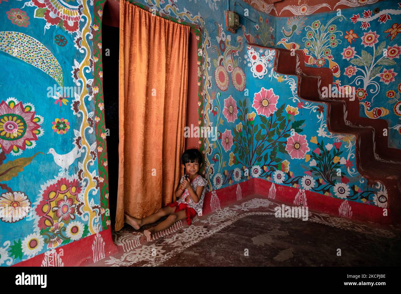 A child poses in front of a colorfully painted house in alpona village in chapainawabganj, Bangladesh. (Photo by Mushfiqul Alam/NurPhoto) Stock Photo