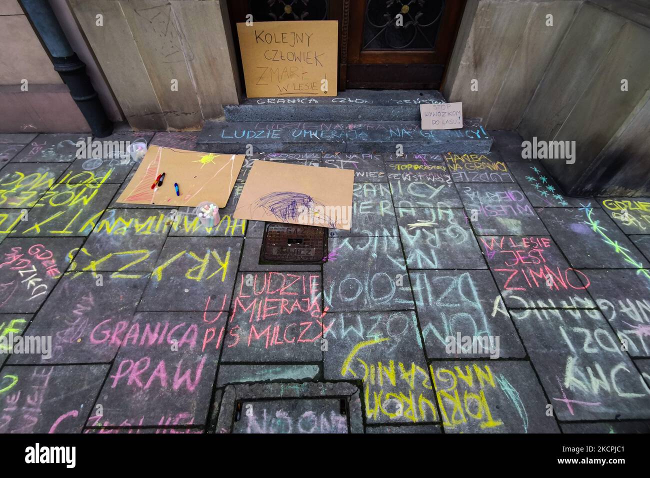 Chalk drawings and slogans were put on the pavement in front of Law and Justice (PiS) ruling party's office during a protest against the government's treatment of refugees, on the day when Syrian migrant was found dead on Polish-Belarusian border. Krakow, Poland on October 14, 2021. Few days before, a group of mothers with children, who are the representatives of 'Family Without Borders' initiative, made chalk drawings on the sidewalks in front of the headquarters of the Law and Justice party on Retoryka Street in Krakow. The police that arrived at the place, confiscated chalk and drawings wer Stock Photo