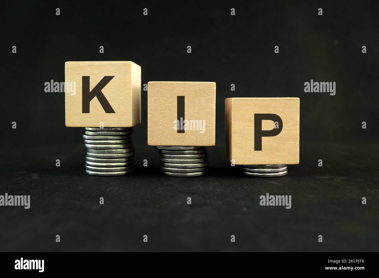 Laotian kip currency weakening, value depreciation and devaluation concept. Decreasing stack of coins on dark black background. Stock Photo