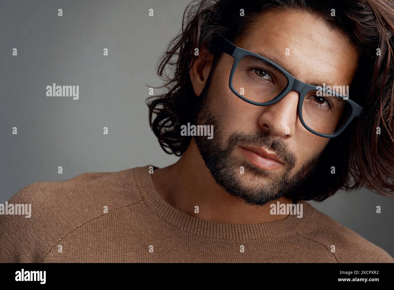 Eye catching frames that suit his face. Studio shot of a handsome young man wearing glasses against a gray background. Stock Photo