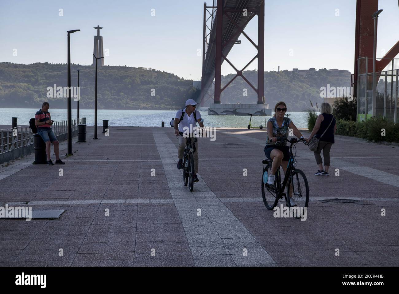 Two people on bicycles ride around the 25 de Abril bridge, Lisbon. 20 October 2021. In mainland Portugal, the simultaneous administration of influenza and covid-19 vaccines began, with the General Health Authority (DGS) planning to vaccinate around two million people in this modality. (Photo by Jorge Mantilla/NurPhoto) Stock Photo
