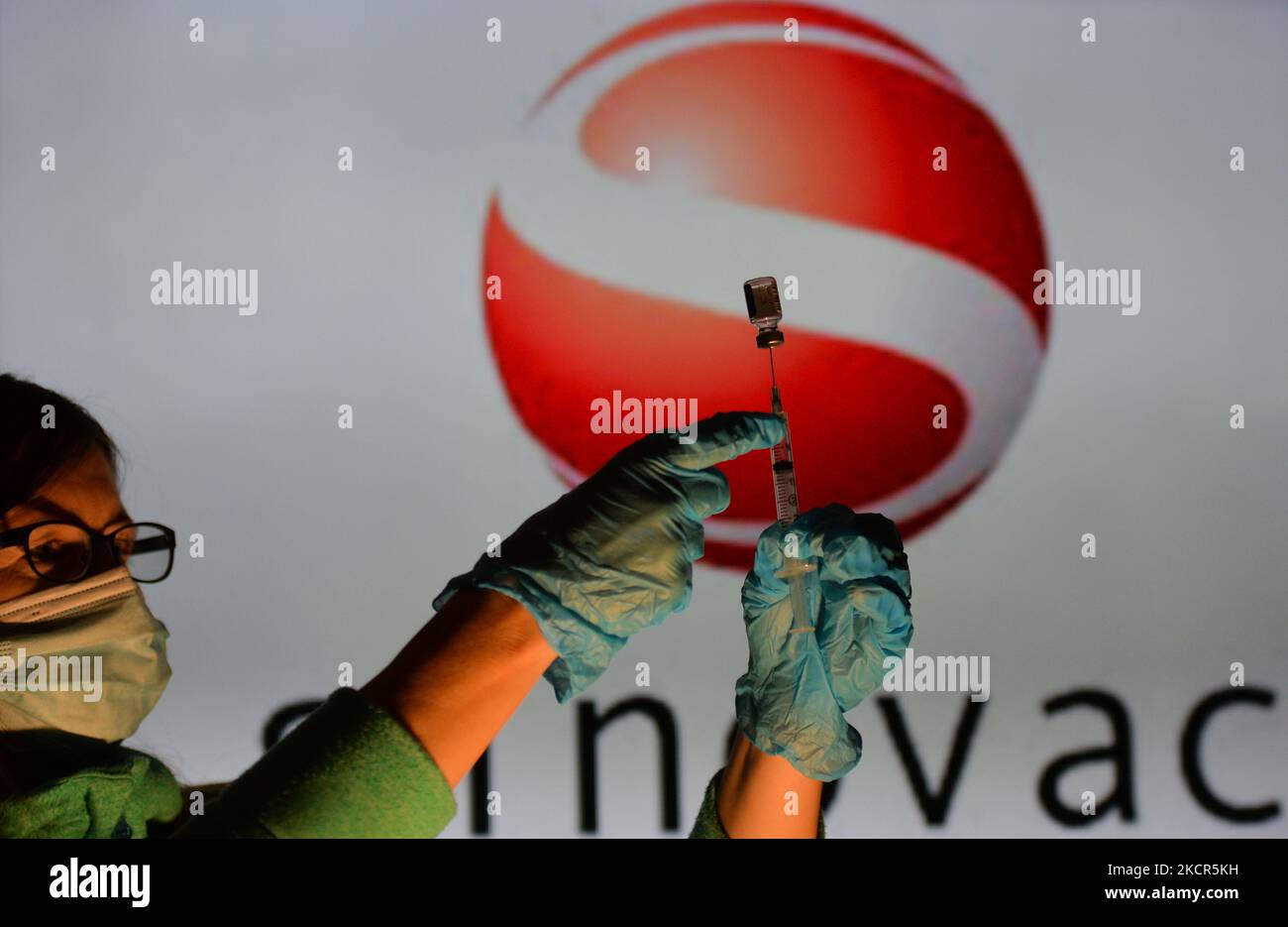 An illustrative image of a person holding a medical syringe and a vaccine vial in front of the Sinavac logo displayed on a screen. On Thursday, October 21, 2021, in Edmonton, Alberta, Canada. (Photo by Artur Widak/NurPhoto) Stock Photo