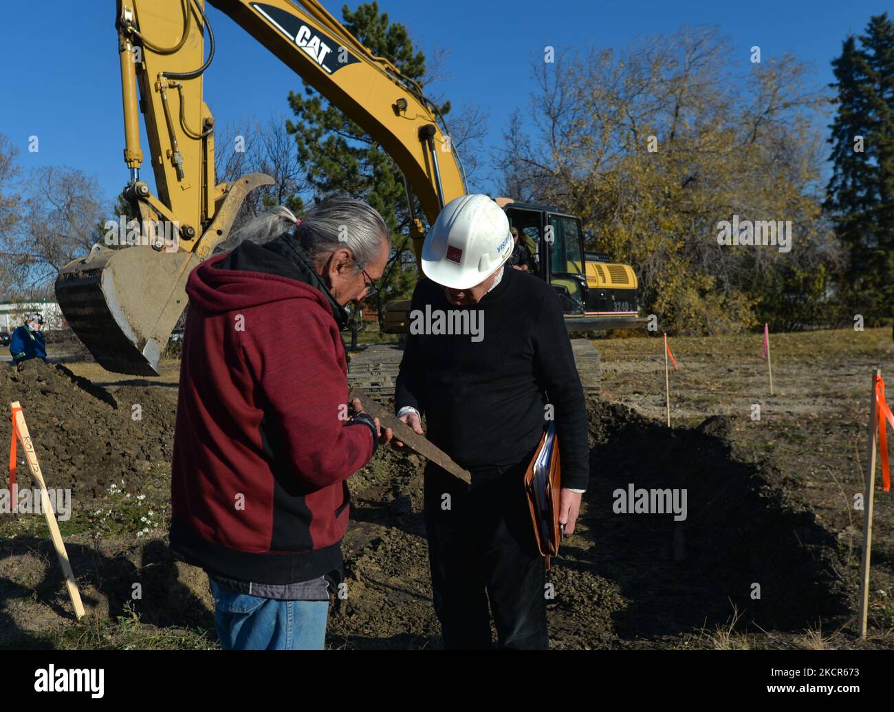Elder Fernie Marty from the Papaschase First Nation, checks a found piece of wood with architect Gene Dub, as he monitors excavations on the grounds of the former Charles Camsell Hospital, in Edmonton. Second phase of excavation work began today at the site of the former Charles Camsell Hospital, the Edmonton facility that for decades was used to treat Indigenous people with tuberculosis. First Nation members have been calling for construction to stop at the grounds where many believe patients may have been buried. The search is being funded by the property's developer. On Thursday, 21 October Stock Photo
