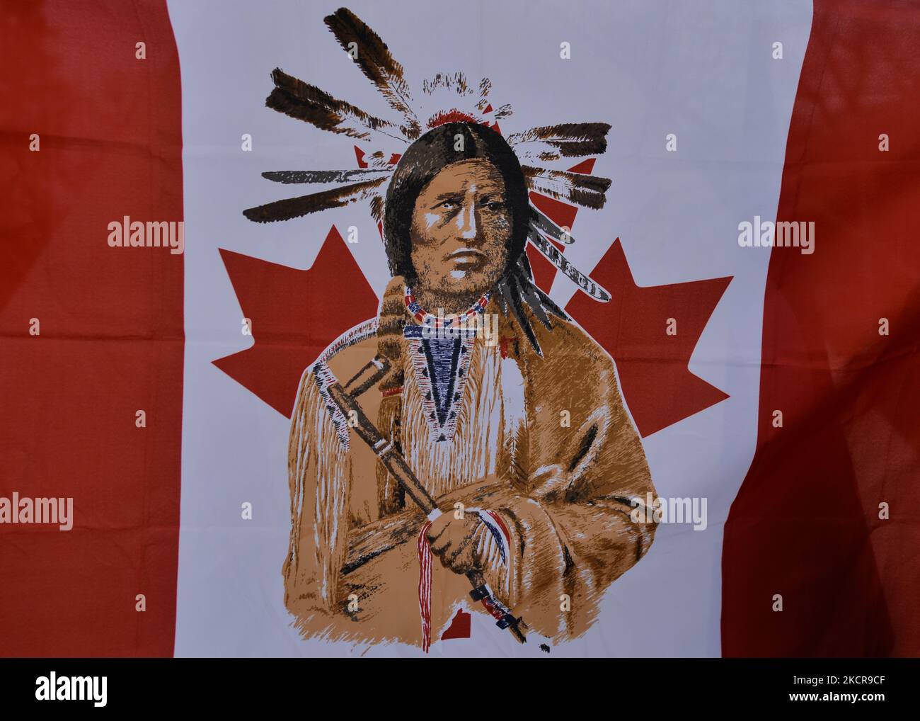 A modified Canadian flag with an image of a First Nations member in the center, seen inside a 'sit-in' camp that consists of five teepees, a dozen tents and a sacred fire, set in the Alberta Legislative Grounds. About 50 people have been in the camp that began in early October. Their aim is to raise awareness of issues facing First Nations communities in Alberta and Canada, including the claim of territory, and the issue of unmarked graves of indigenous children. On Friday, 22 August 2021, in Alberta Legislature Grounds, Edmonton, Alberta, Canada. (Photo by Artur Widak/NurPhoto) Stock Photo