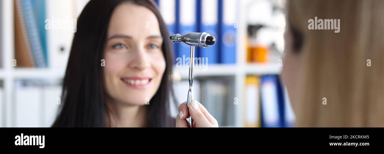 Neurologist doctor driving hammer tool in front of patient eyes in clinic Stock Photo