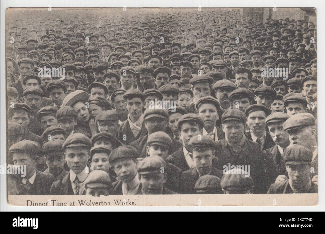 Dinner time at Wolverton Works, c.1909. Photograph of a huge crowd of workers employed at the Wolverton railway works, Buckinghamshire, during their lunch break. Almost all of the employees in the picture are young men wearing flat caps. This postcard was produced as part of the W.J. Hutchinson series, Wolverton, and was posted in 1909 Stock Photo