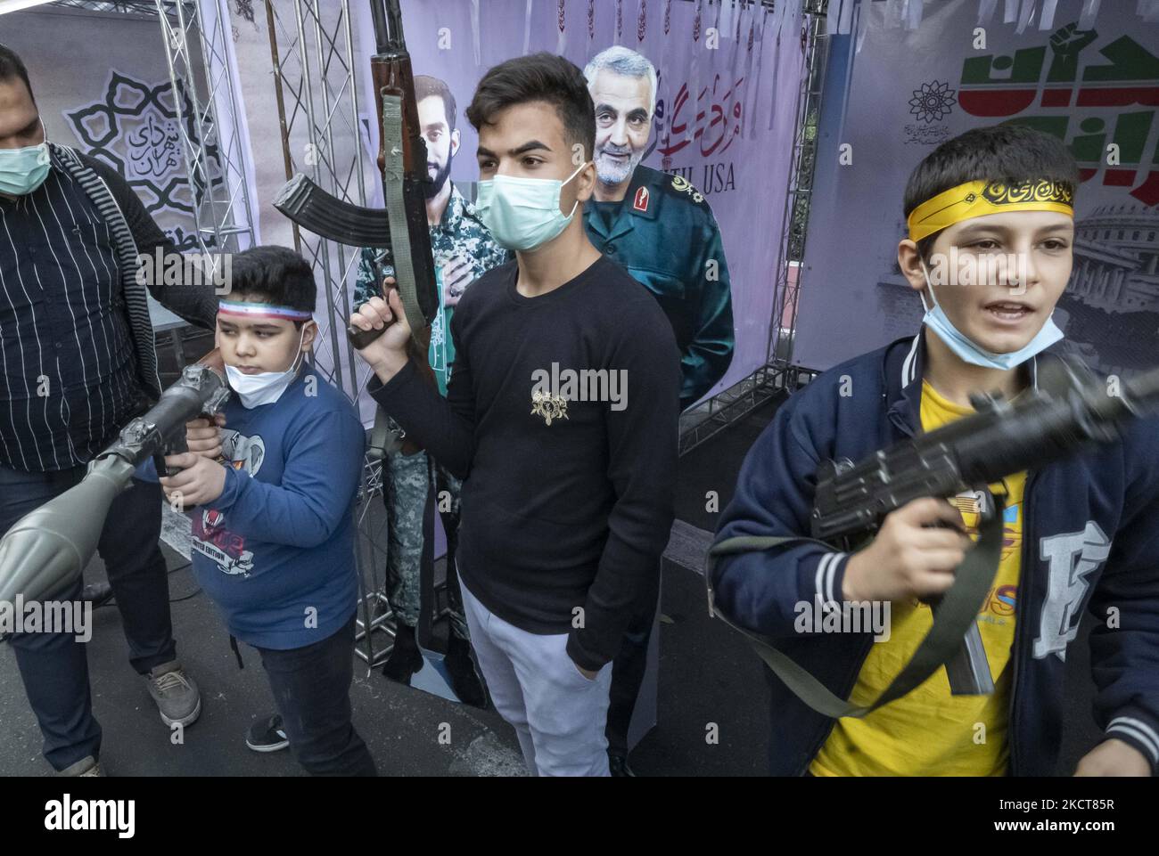 Iranian schoolboys hold AK-47 gun, RPG-7 rocket-launcher and a UZI-gun as they pose for photographs in front of an effigy of the Iranian former commander of the Islamic Revolutionary Guard Corps’ (IRGC) Quds Force, General Qasem Soleimani, during a ceremony to mark the anniversary of the seizure of the U.S. embassy in downtown Tehran, November 4, 2021. (Photo by Morteza Nikoubazl/NurPhoto) Stock Photo