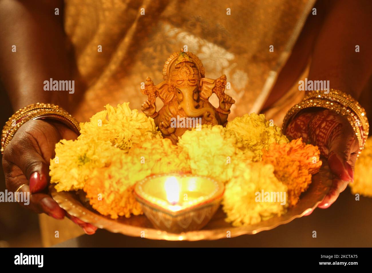 Hindu devotee holds a tray with flowers and a diya (small clay lamp) by an idol of Lord Ganesh during the festival of Diwali at a Hindu temple in Toronto, Ontario, Canada, on November 04, 2021. (Photo by Creative Touch Imaging Ltd./NurPhoto) Stock Photo