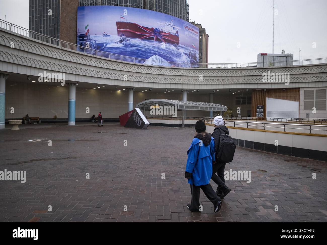 Two Iranian young women walk under a giant anti-U.S. billboard that is hanged on a wall of a state building in downtown Tehran, November 5, 2021. On November 3rd, 2021 an oil tanker carrying Iranian oil was seized in the Oman Sea and directed to an unknown destination, but the IRGC navy seized the Iranian tanker and directed it to Iranian territorial waters by carrying out Operation heliborne on the tanker deck. According to a report by the U.S. Navy News Network. (Photo by Morteza Nikoubazl/NurPhoto) Stock Photo
