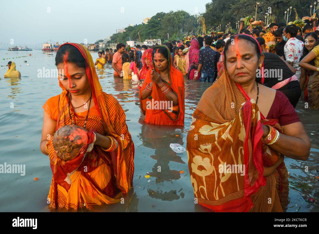 Devotees offer prayer and gifts to Sun god , during sunset time at a ...