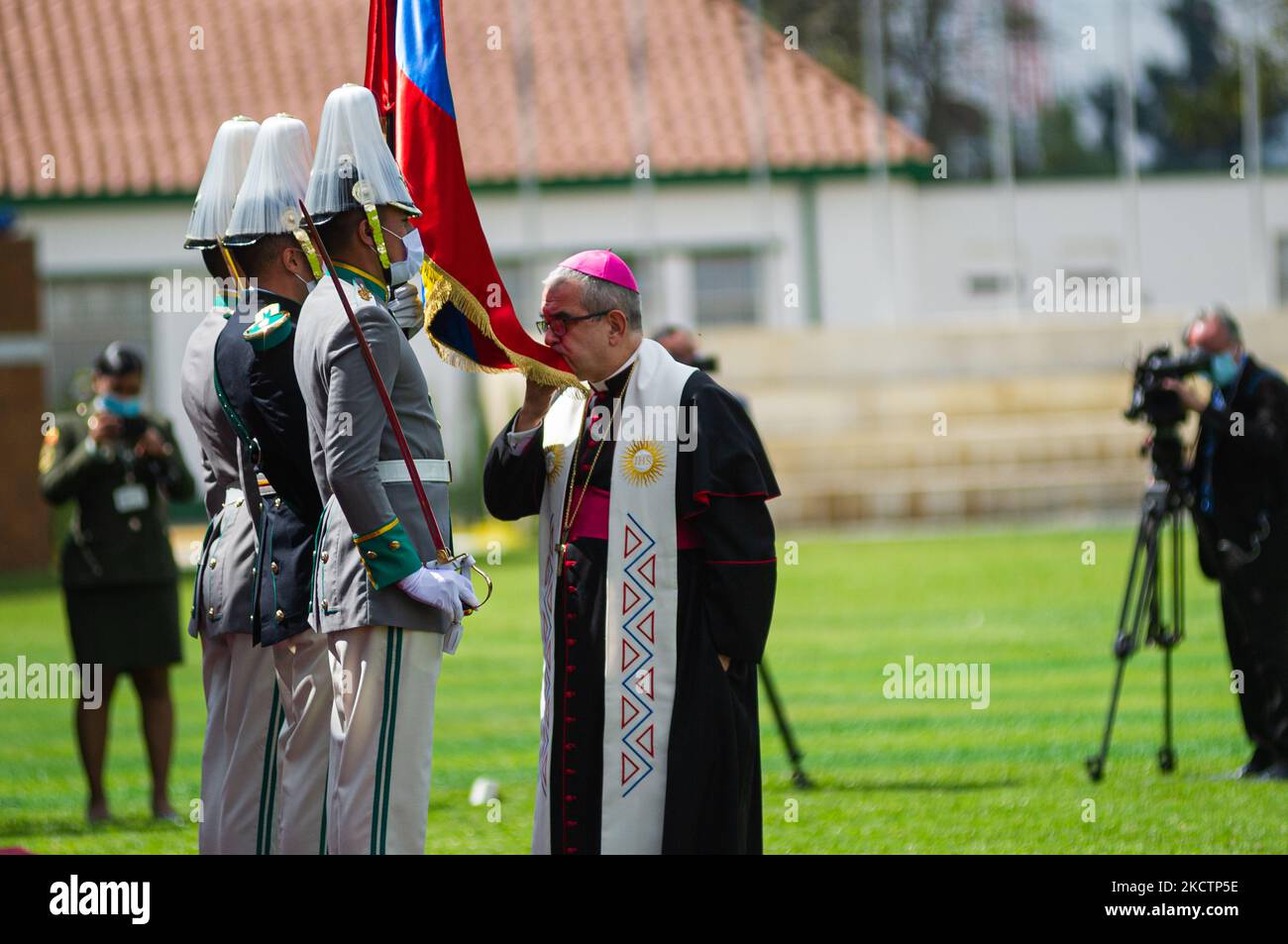 A priest kisses the Colombian flag during an event were Colombia's president Ivan Duque Marquez and Colombia's Minister of Defense Diego Molano in conmmemoration of the 130 anniversary of Colombia's National Police and the promotion to officers to more than a 100 police members, in Bogota, Colombia on November 11, 2021. (Photo by Sebastian Barros/NurPhoto) Stock Photo