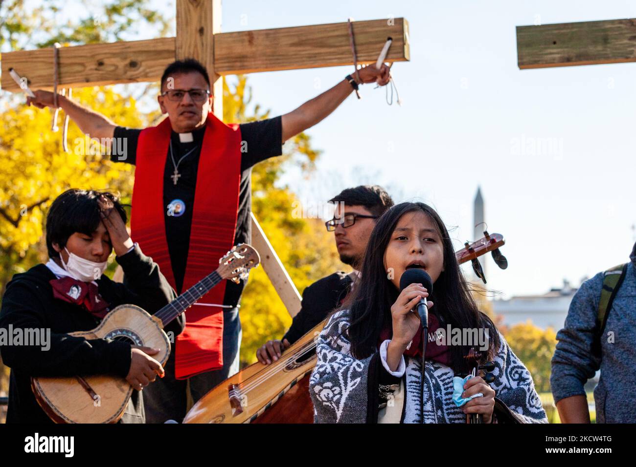 Immigration activist Father Jose Landaverde hangs on a wooden cross during a direct action by the National TPS Alliance at the White House. Activists are hanging on crosses for 8 hours to symbolize the sacrifice immigrants make to contribute to life in the US by long, hard work. A band of young people from a mariachi school plays in front of Father Landaverde. They are part of a rally celebrating Mexican President Andrés Manuel Lopez Obrador’s summit with President Joe Biden and Canadian Peime Minister Justin Trudeau, as well as demanding immigration reform. (Photo by Allison Bailey/NurPhoto) Stock Photo