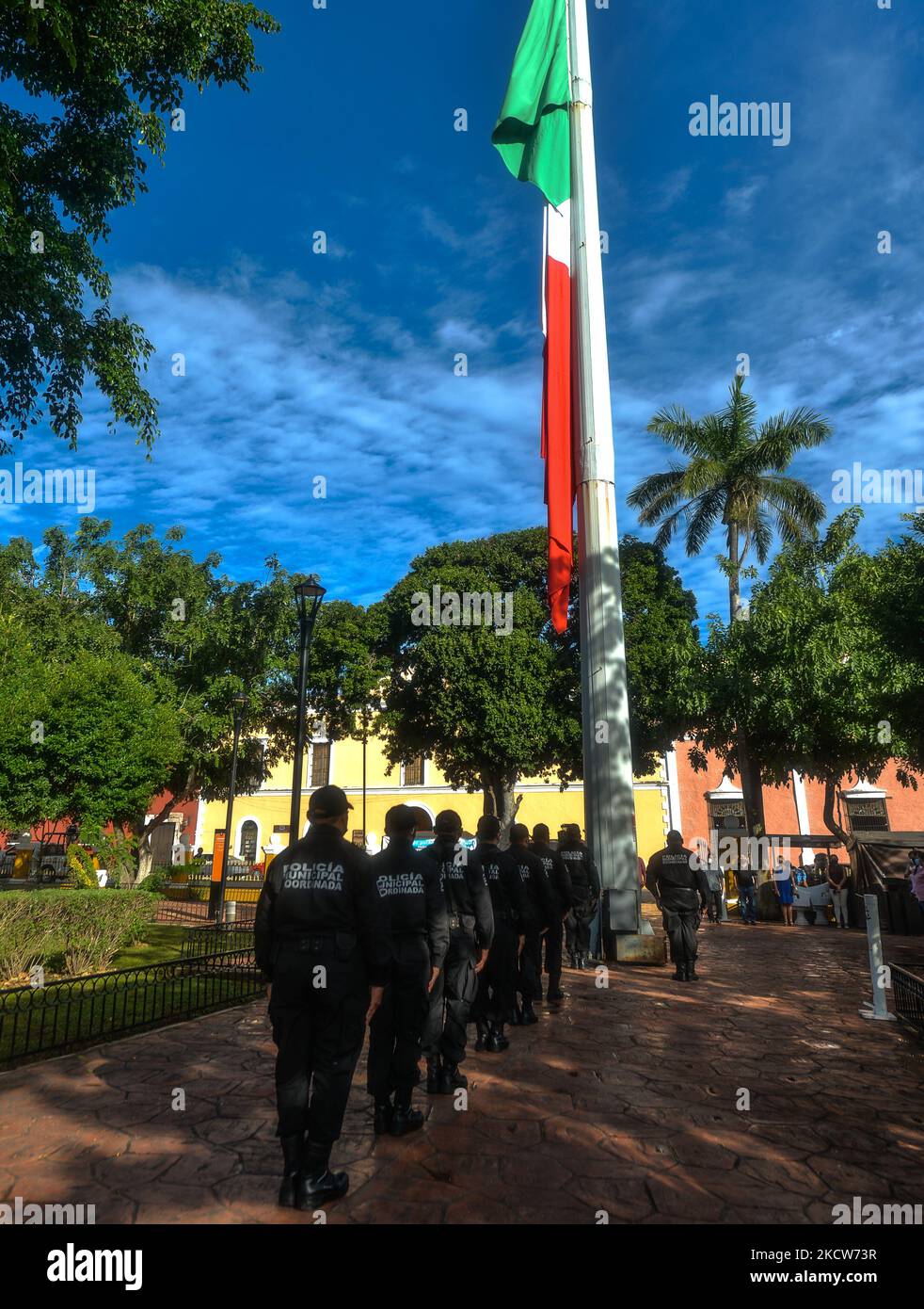 Members of the municipal police (Policía Municipal de Valladolid) in front of the large national flag of Mexico during the short ceremony of El Día de la Revolucion (Revolution Day), a national holiday commemorating the beginning of the Mexican Revolution on November 20, 1910. Official Revolution Day celebrations have been canceled due to the Covid-19 pandemic. The city of Valladolid was the site of the 'first spark of the Mexican Revolution,' also known as the Dzelkoop Plan, an uprising that began on June 4, 1910, by Maximiliano R. Bonilla and other leaders of the Independent Electoral Center Stock Photo