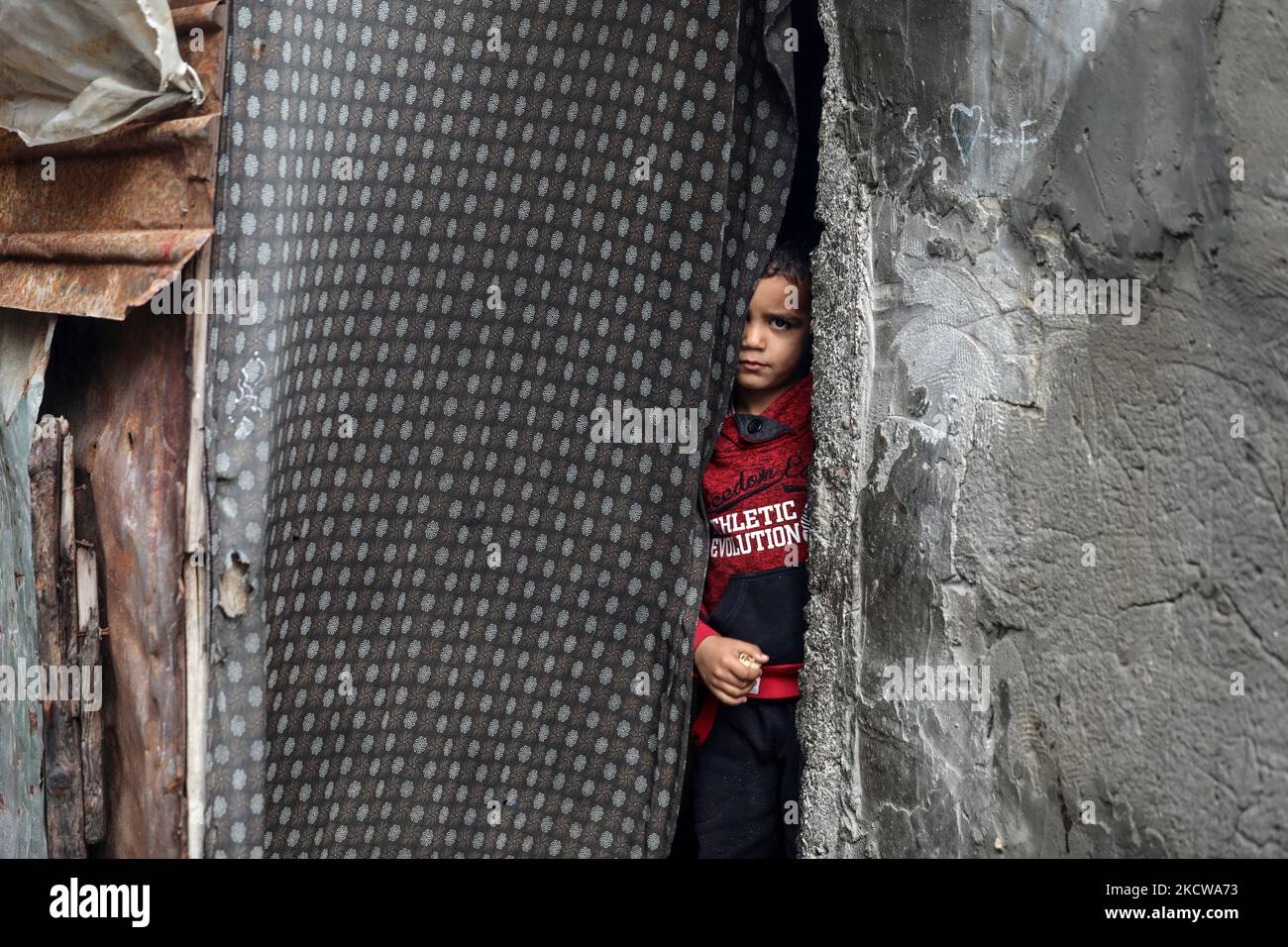 A Palestinian child looks through the gate of his family's house during ...