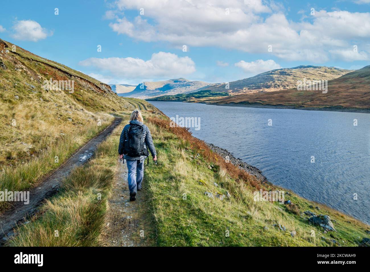 A walker walks the path beside the freshwater loch of Loch Lyon in Perthshire, Scotland Stock Photo