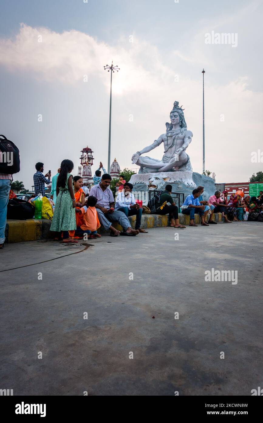 July 4th 2022 Haridwar India. Lord Shiva statue at the Haridwar railway Station with people sitting all around in waiting. Stock Photo
