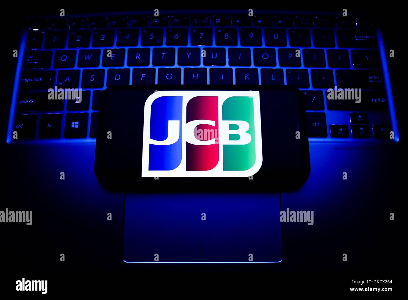 JCB logo displayed on a phone screen and a laptop keyboard are seen in this illustration photo taken in Krakow, Poland on December 1, 2021. (Photo by Jakub Porzycki/NurPhoto) Stock Photo