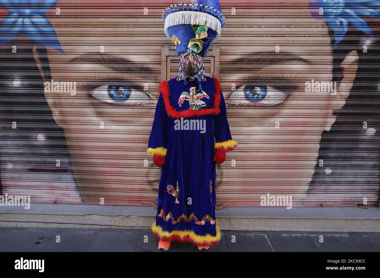 A chinelo poses in front of a shop curtain prior to the First Great Parade  of Huehuenches and Chinelos in Mexico City, which started from the Plaza  Tlaxcoaque to the Zócalo to