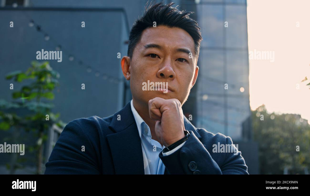 Close-up dreaming thinking pensive 40s Asian Korean man puzzled confused thoughtful decision problem solution. Adult Chinese businessman entrepreneur Stock Photo