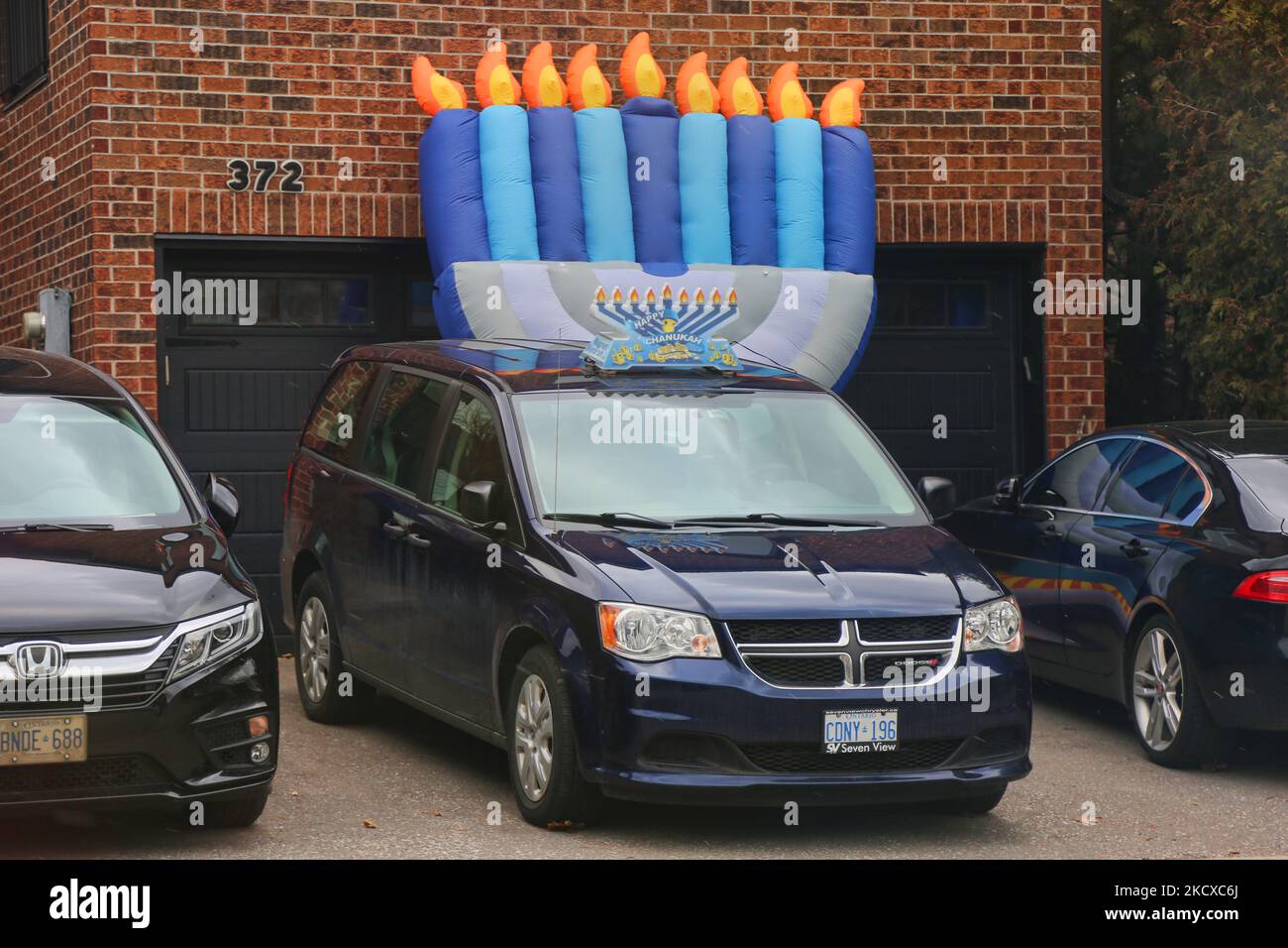 Large inflatable menorah in front of a home by a vehicle with a menorah attached to the roof