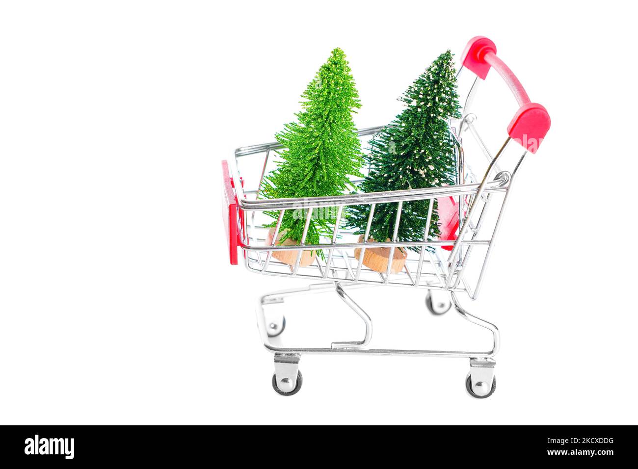 Two toy christmas trees in a miniature shopping trolley isolated on white background with copy