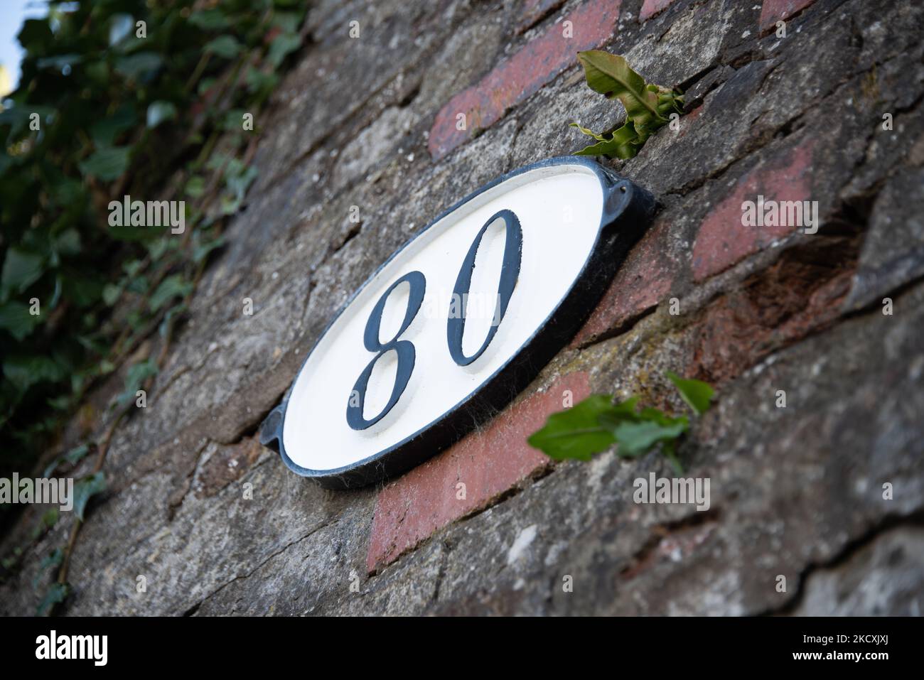 Identification plate on an old bridge over a canal showing the number 80 printed black on a white background Stock Photo